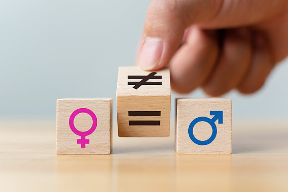 Symbol image; hand turns an equal and an unequal sign between the symbols for male and female gender
